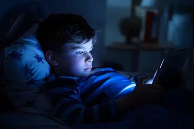 Jugendlicher konzentriert am Handy in dunkler Umgebung