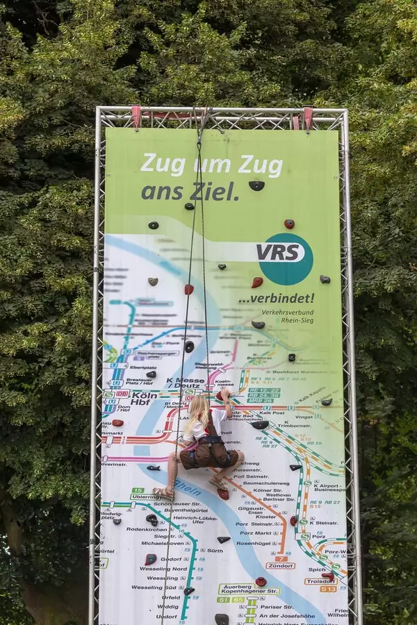 Junge Frau auf einer künstlichen Kletterwand im Look eines U-Bahn Netzplans