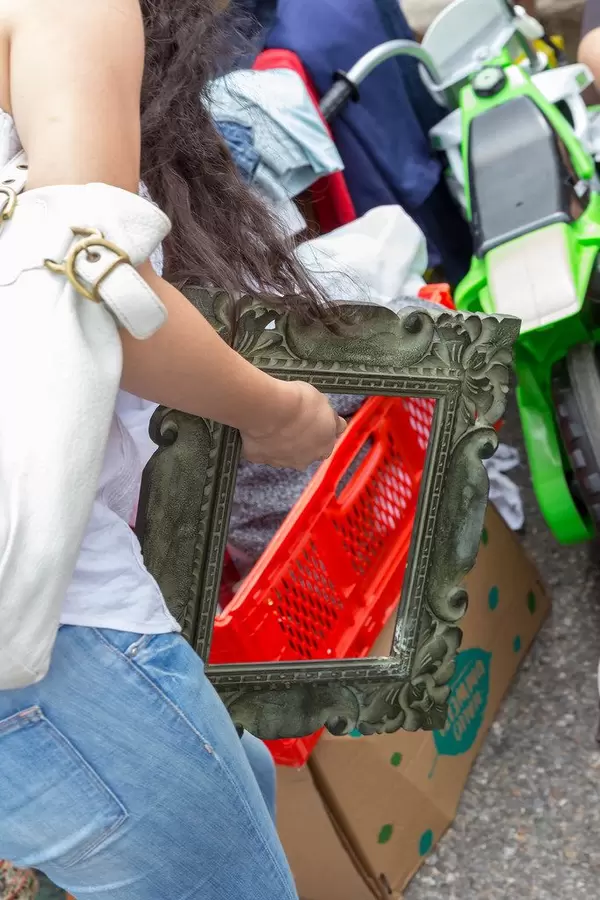 Junge Frau hält einen gebrauchten Bilderrahmen in der Hand