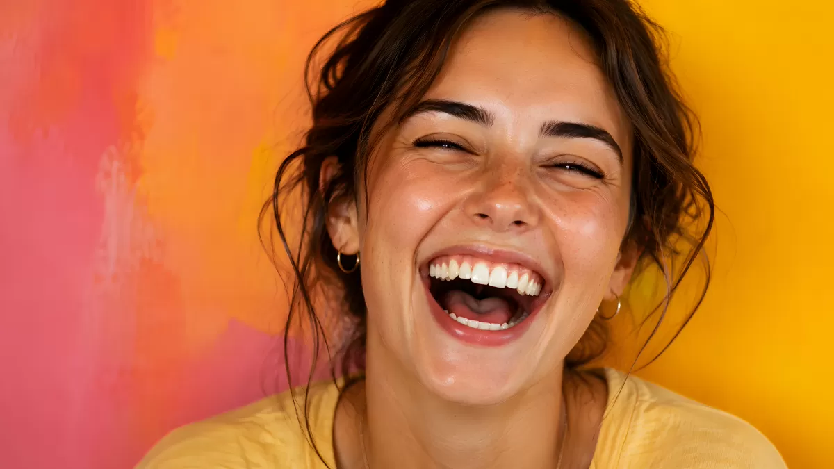 Junge Frau lacht ausgelassen vor buntem Hintergrund