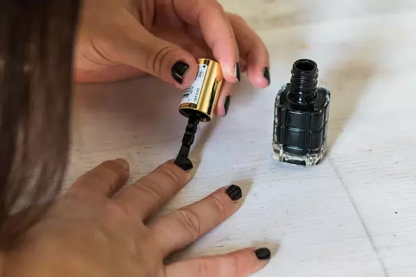 Junge Frau lackiert ihre Nägel mit schwarzem Nagellack