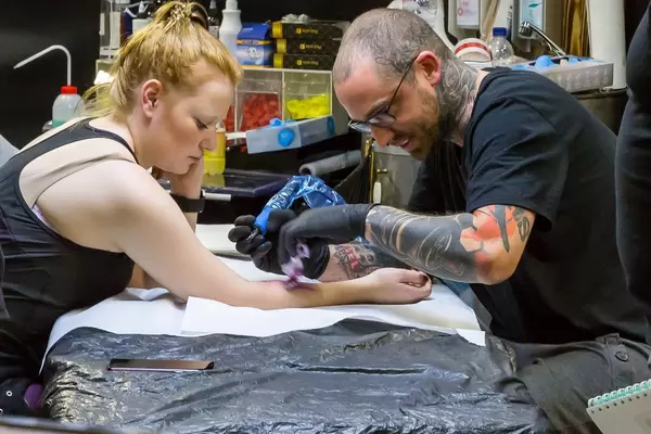 Junge Frau lässt sich tätowieren - FIBO Köln 2018