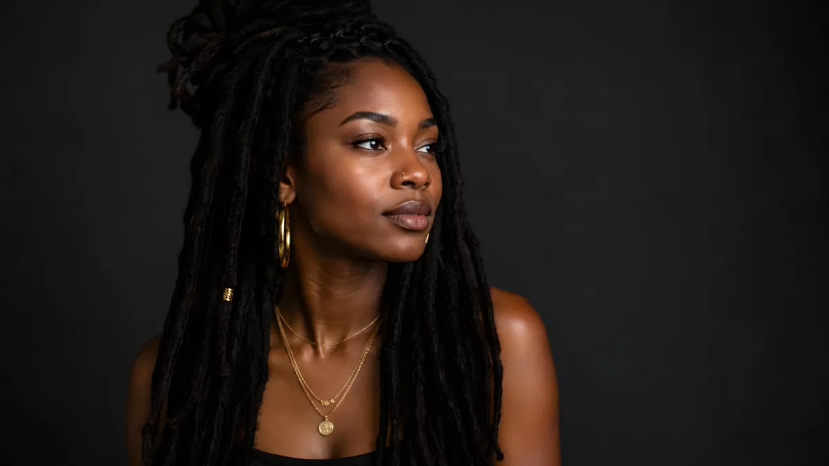 Junge Frau mit Dreadlocks und Goldschmuck im Studio
