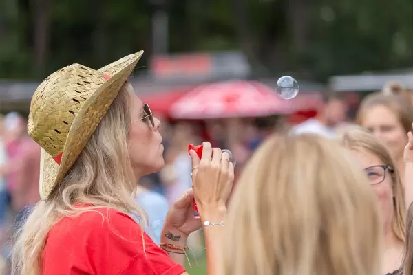 Junge Frau mit geflochtenem Hut macht Seifenblasen