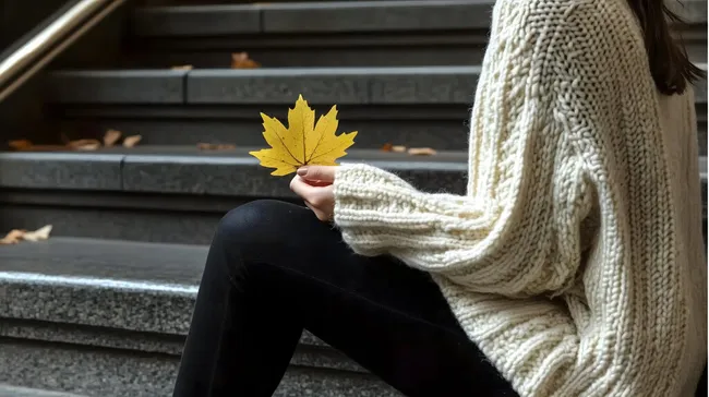 Junge Frau mit Herbstlaub in weißem Pullover