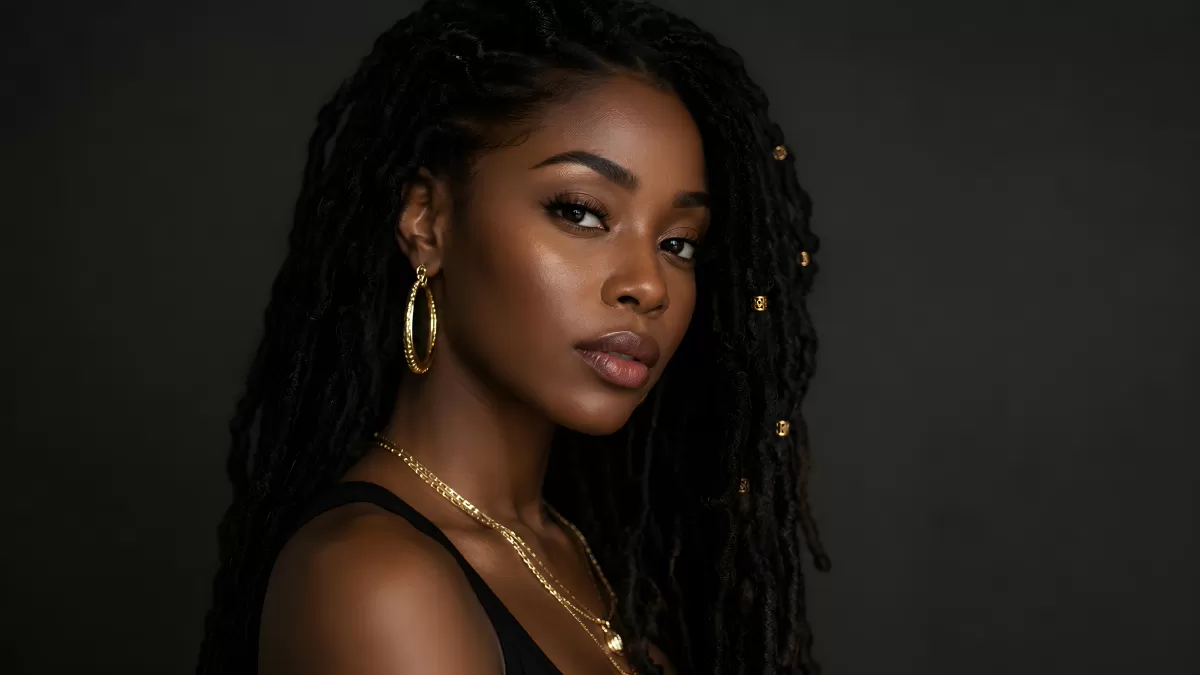 Junge Frau mit Locs und goldenem Schmuck im Studio