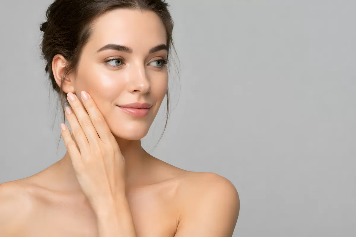 Junge Frau mit makelloser Haut berührt ihr Gesicht