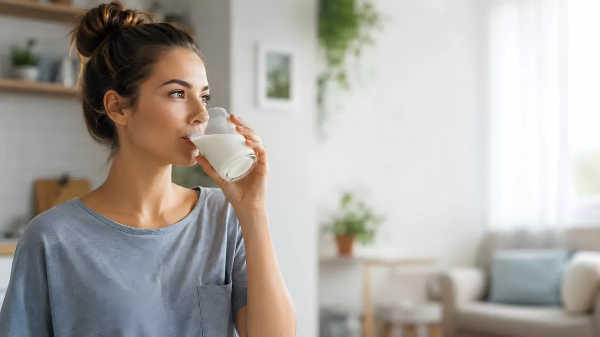 Junge Frau trinkt ein Glas Milch zu Hause