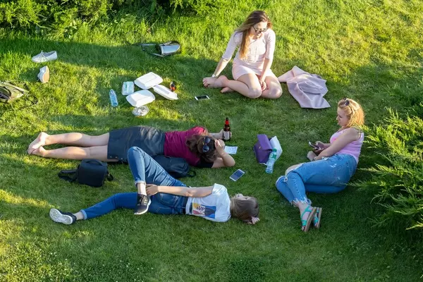 Junge Frauen liegen auf dem Rasen in einem Park in Moskau
