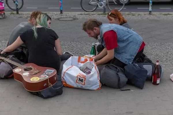 Junge Menschen mit Gitarre sitzen auf dem Gehsteig