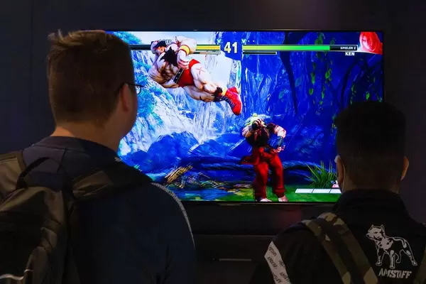 Junge Messebesucher zocken Videospiel im Zweispieler-Modus, auf einem Panasonic-Bildschirm