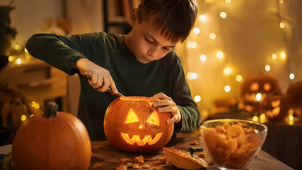 Junge schnitzt leuchtenden Halloween-Kürbis zu Hause