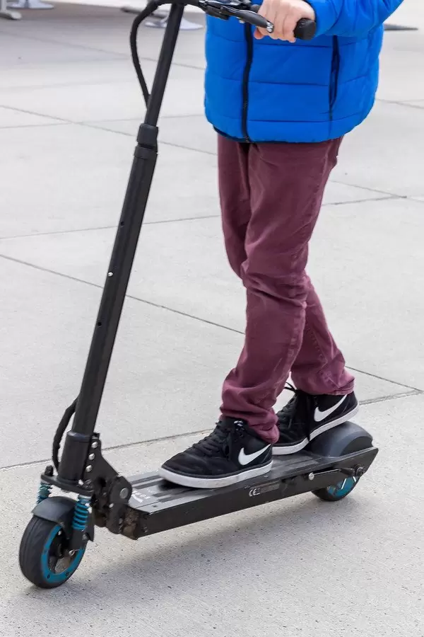 Junge steht auf dem Egret One Elektroroller und fährt über die E-Cologne Messe