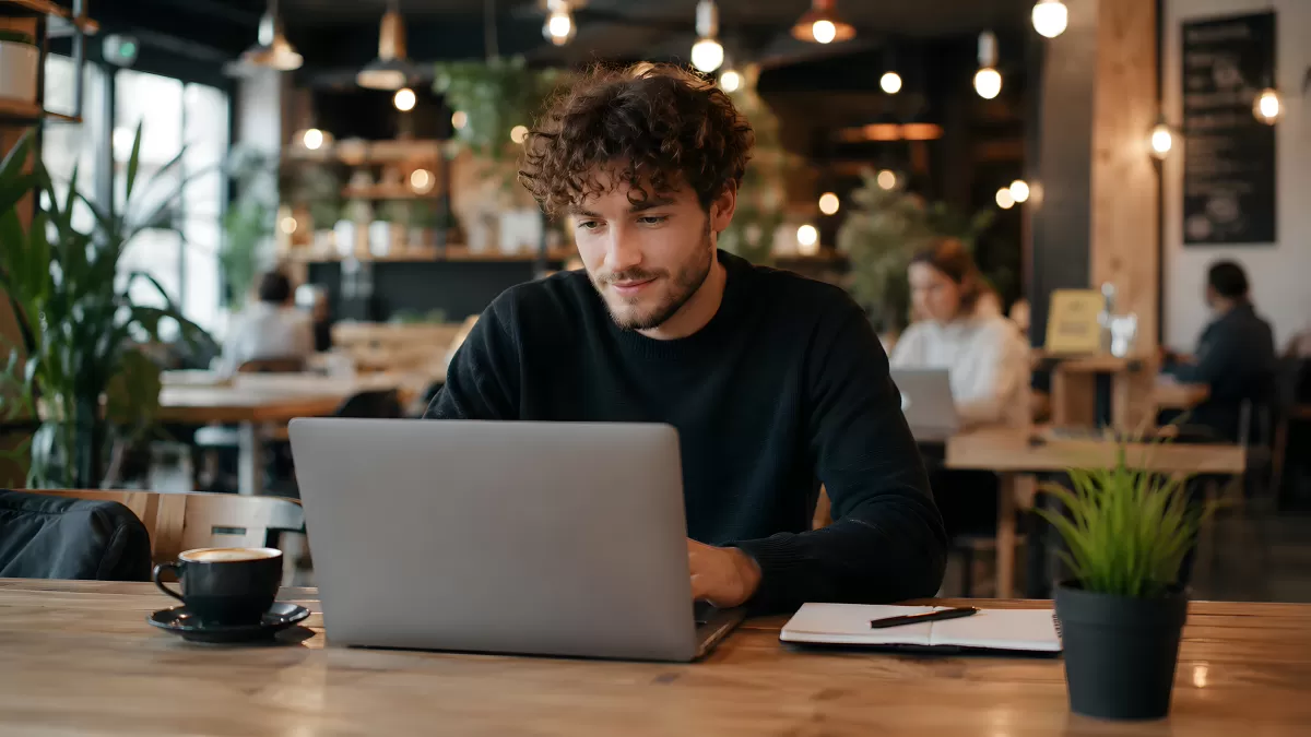 Junger Mann arbeitet mit Laptop in modernem Café