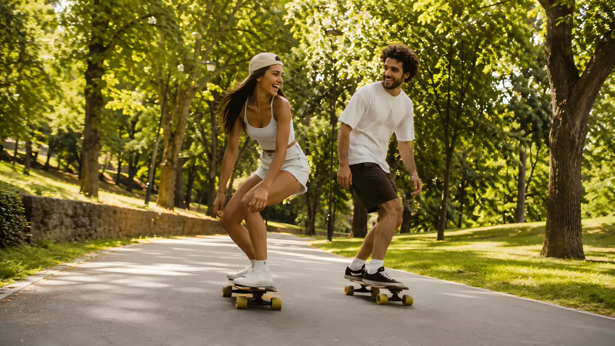 Junges Paar fährt Skateboard im sommerlichen Park