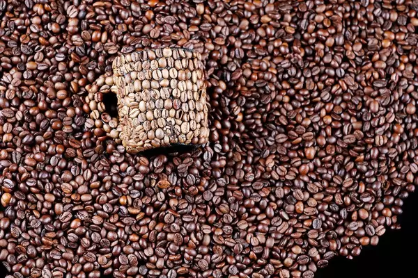Kaffeebohnen Tasse liegt in Kaffeebohnen