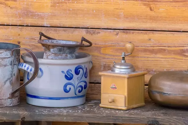 Kaffeemühle und Tontopf vor Holzwand