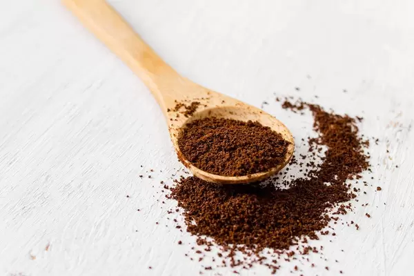 Kaffeepulver in einem Holzlöffel auf weißem Hintergrund