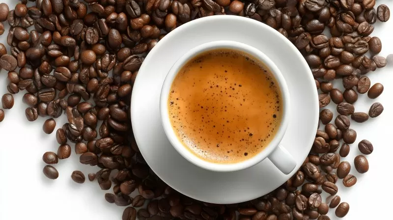 Kaffeetasse mit Crema umgeben von gerösteten Kaffeebohnen