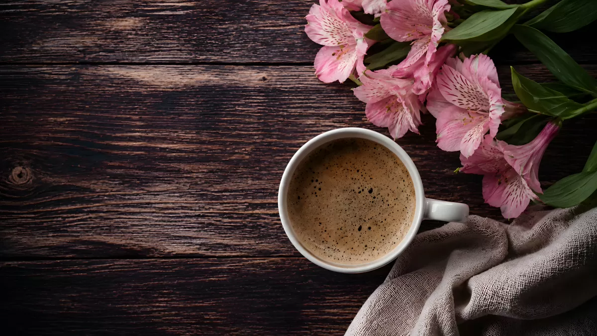 Kaffeetasse mit rosa Alstromerien auf dunklem Holz