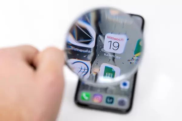 Kalender Smartphone App Logo durch Lupe fotografiert vor weißem Hintergrund