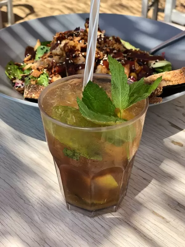 Kaltes Getränk mit Minzblättern & Strohhalm und griechischer Salat mit Hähnchenfleisch, Tomaten, Mais, Zwiebeln, Sesam und Barbecuesauce