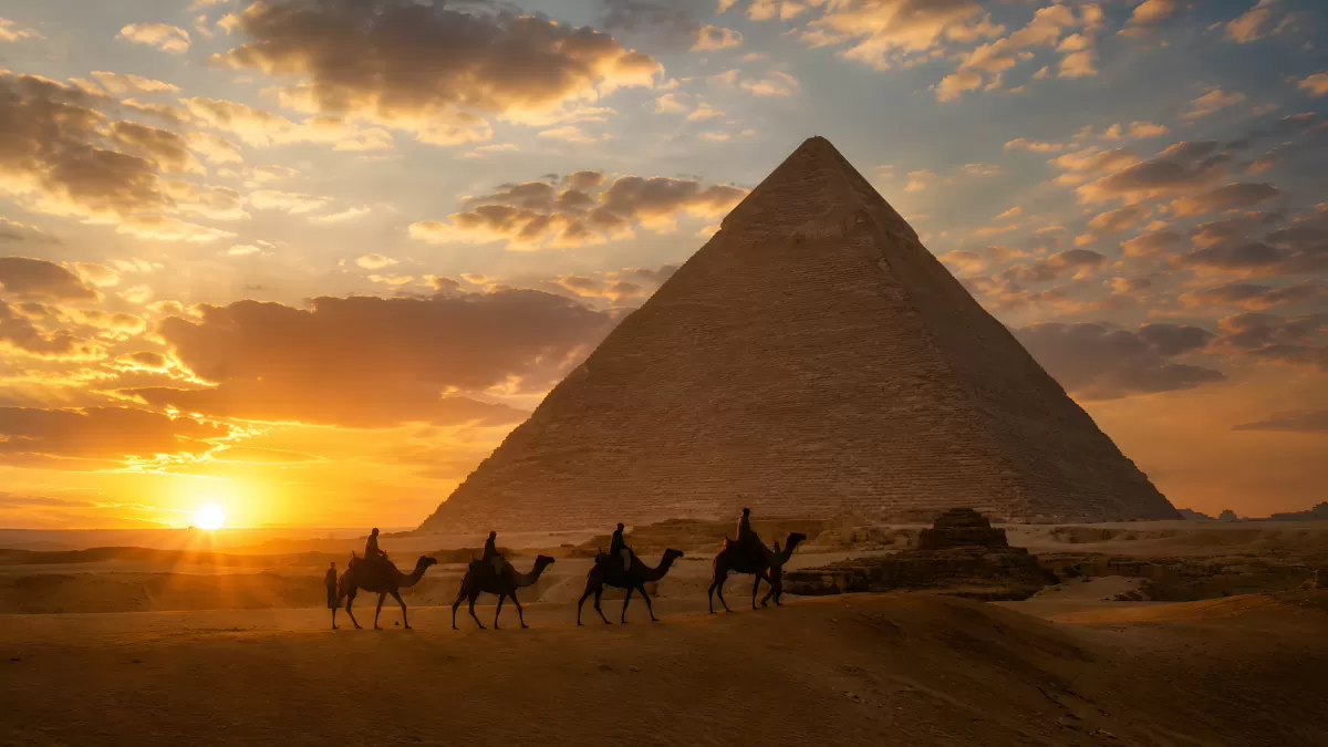 Kamelkarawane vor der Pyramide von Gizeh bei Sonnenuntergang