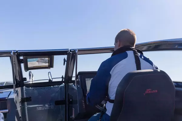 Kapitän steuert ein Yamarin Schnellboot an seinem Display, vor blauem Himmel