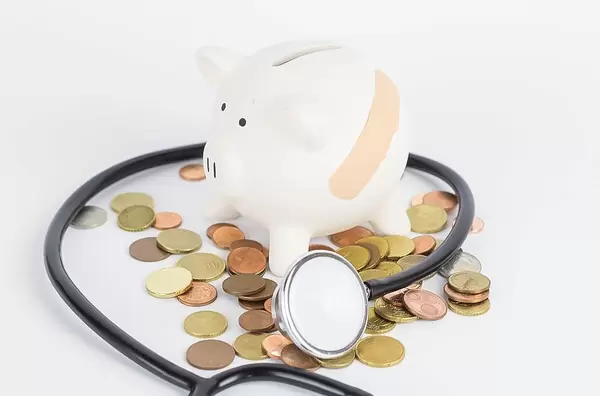 Kaputtes Krankensystem mit verletzter Spardose und Kleingeld