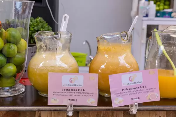 Karaffen mit frisch gepressten Smooties aus verschiedenen Früchten und Glasschale mit Limetten