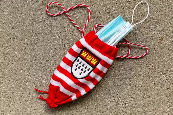 Karneval und Corona: 11.11.2020 in Köln. OP-Maske in rot/weißem Kölschglashalter mit Kölner Wappen