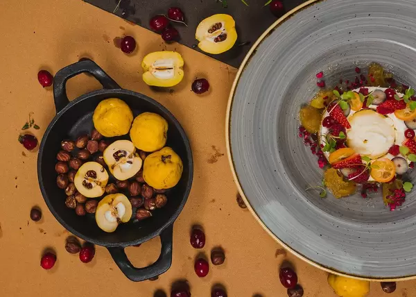 Karottenkuchen auf einem Teller, mit Quitte, Haselnüssen und Beeren