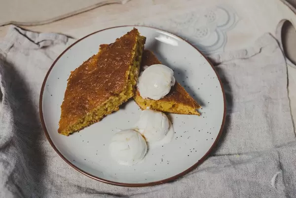 Karrottenkuchen in Diamantenform mit drei Vanille-Eiskugeln auf einem Holztablett serviert