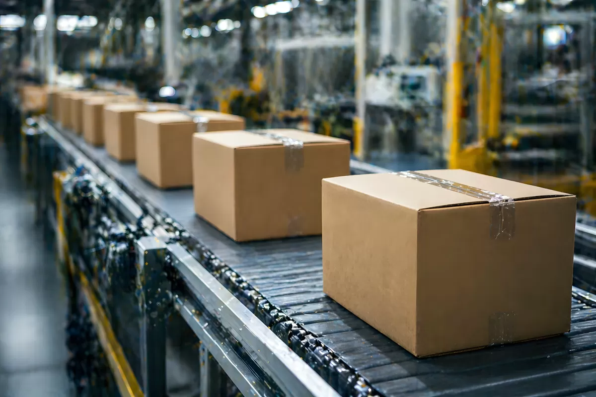 Kartonpakete auf Förderband in Logistikhalle