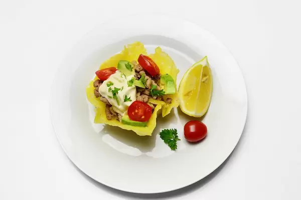 Käsekörbchen gefüllt mit Fleisch, Gemüse, Mayonnaise und Kräutern mit Zitrone auf Teller