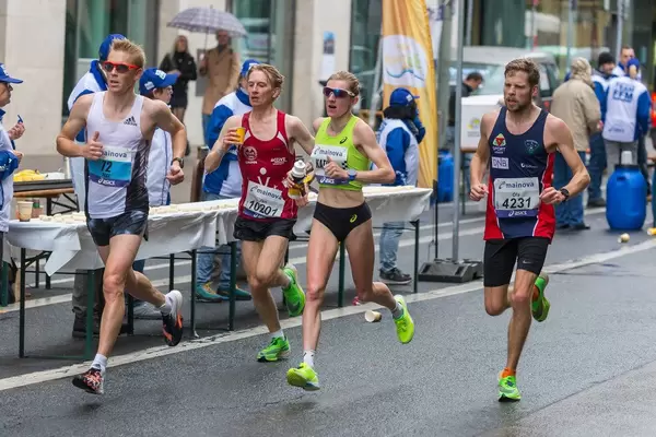 Katha Steinruck umgeben von drei männlichen Athleten passieren die Verpflegungsstation