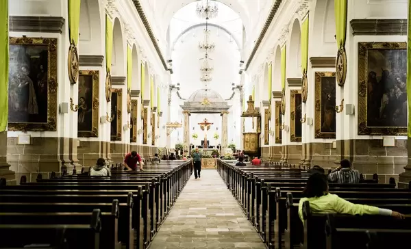 Katholische Kathedrale in Guatemala von innen mit religiösen Bildern, Holzbänken, Altar und einigen Gläubigen