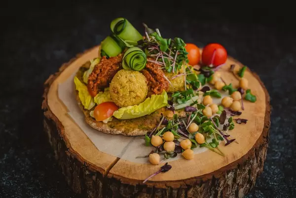 Katsu-Hähnchen-Bällchen garniert mit gekochten Kichererbsen, Kresse, Gurke und rotem Pesto - Nahaufnahme frontal