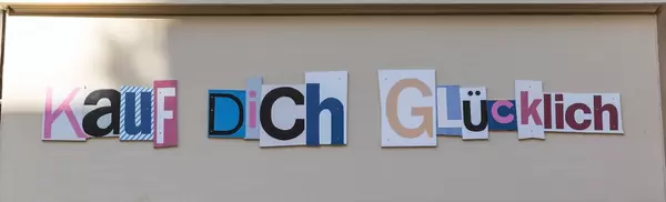 Kauf dich Glücklich Schriftzug auf Hauswand
