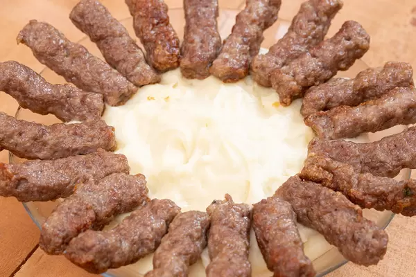 Kebabs arranged in the circle on the plate with mashed potatoes