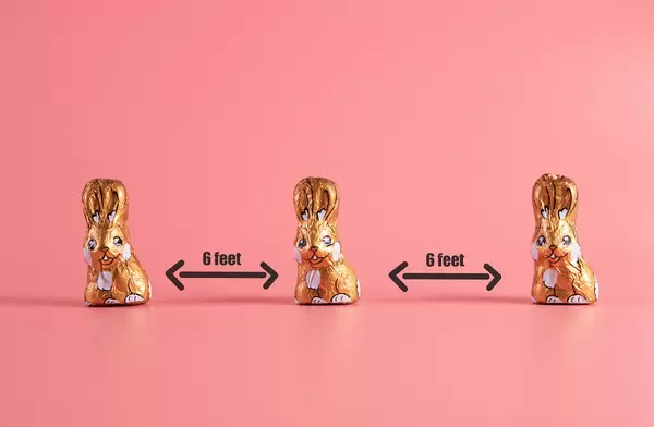 Keep your distance concept with chocolate easter bunnies on pink background