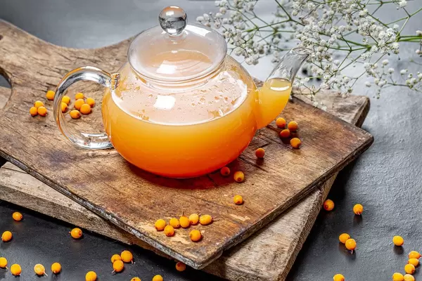 Kettle with fresh sea buckthorn hot drink on a dark background (Flip 2019)