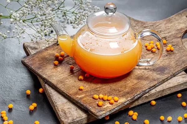 Kettle with fresh sea buckthorn hot drink on a dark background