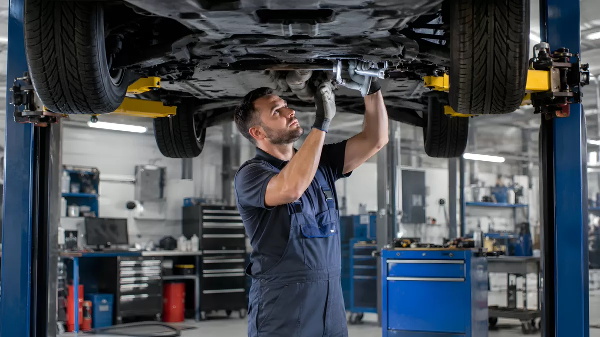 Kfz-Mechaniker arbeitet unter angehobenem Fahrzeug
