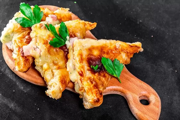 Khachapuri with cheese and ham on black background