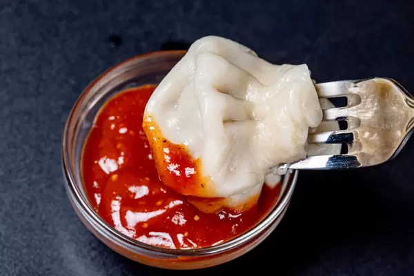 Khinkali soaks in red sauce on a black background