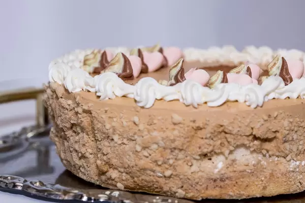 Kiev Torte mit Dekoration aus Sahne und Nüssen auf Metallplatte vor weißem Hintergrund