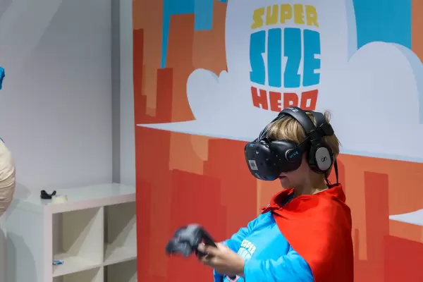Kind im Superhelden-Kostüm spielt mit VR-Brille