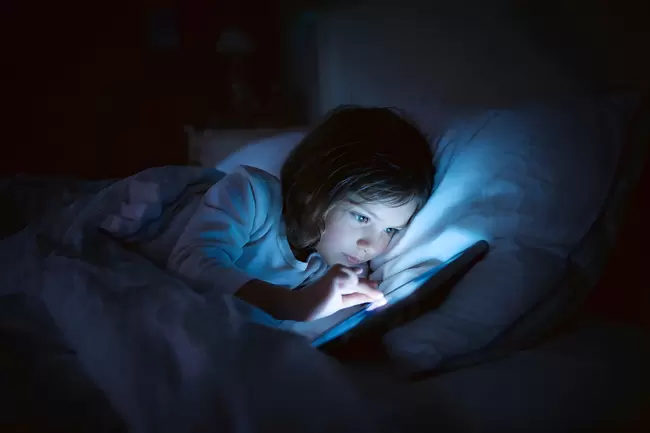 Kind spät nachts mit Smartphone im Bett