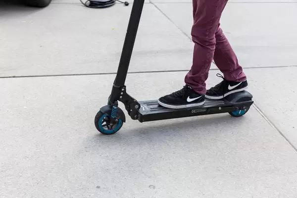 Kind steht auf einem schwarz-blauen Egret One E-Roller auf der E-Cologne Outdoormesse für nachhaltige Mobilität